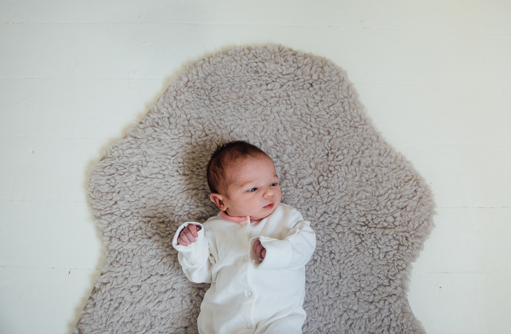 NEWBORN BABY GIRL ON SHEEPSKIN RUG WHITE FLOORBOARDS FAMILY PHOTOGRAPHER KENT