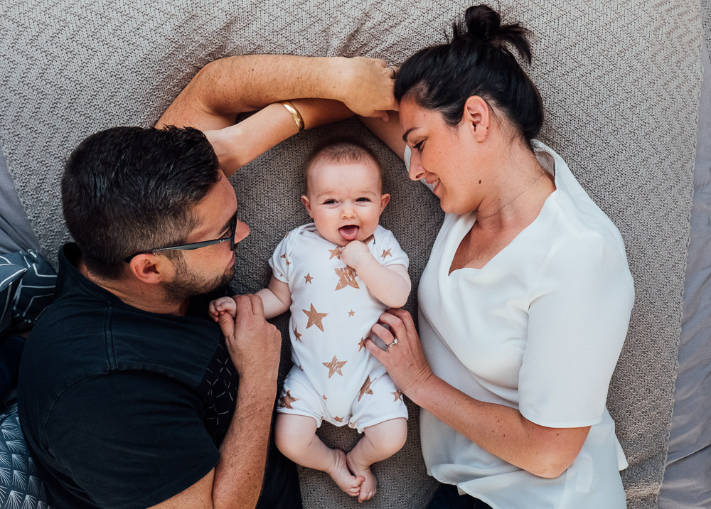 Surrey Family Photographer parents and baby girl on bed smiling